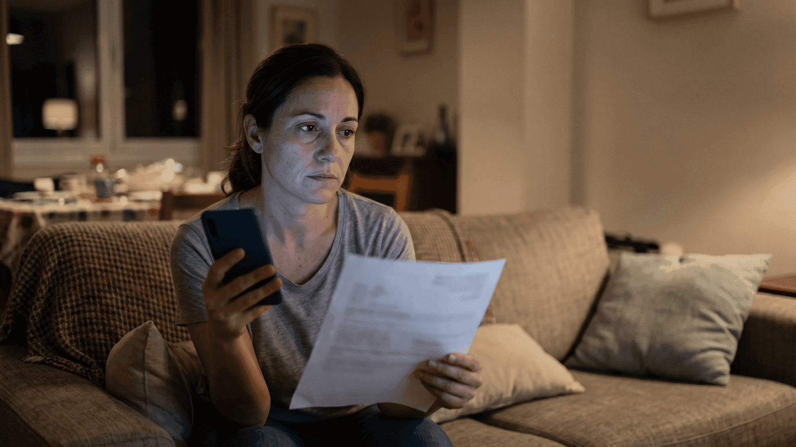Una madre duda con el móvil en la mano y un informe médico en la otra, de noche